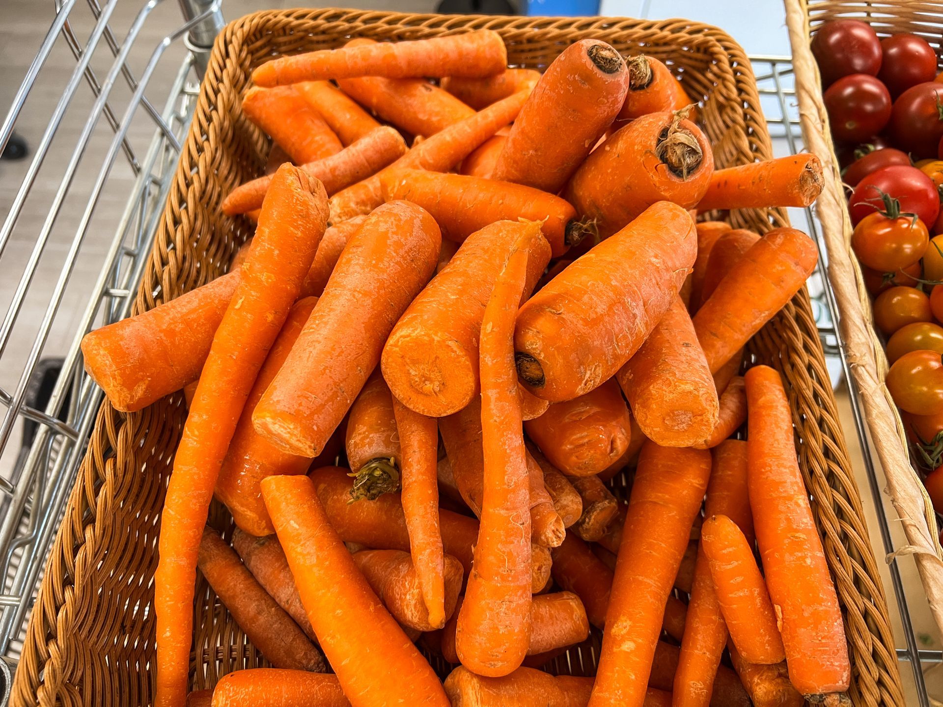 A basket of carrots is sitting on a shopping cart