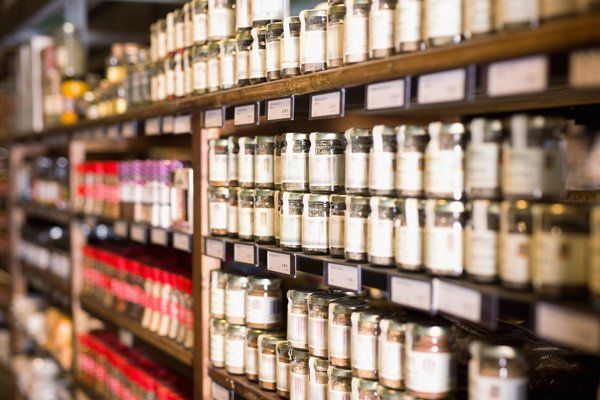 A blurred image of a grocery store aisle filled with jars and bottles.