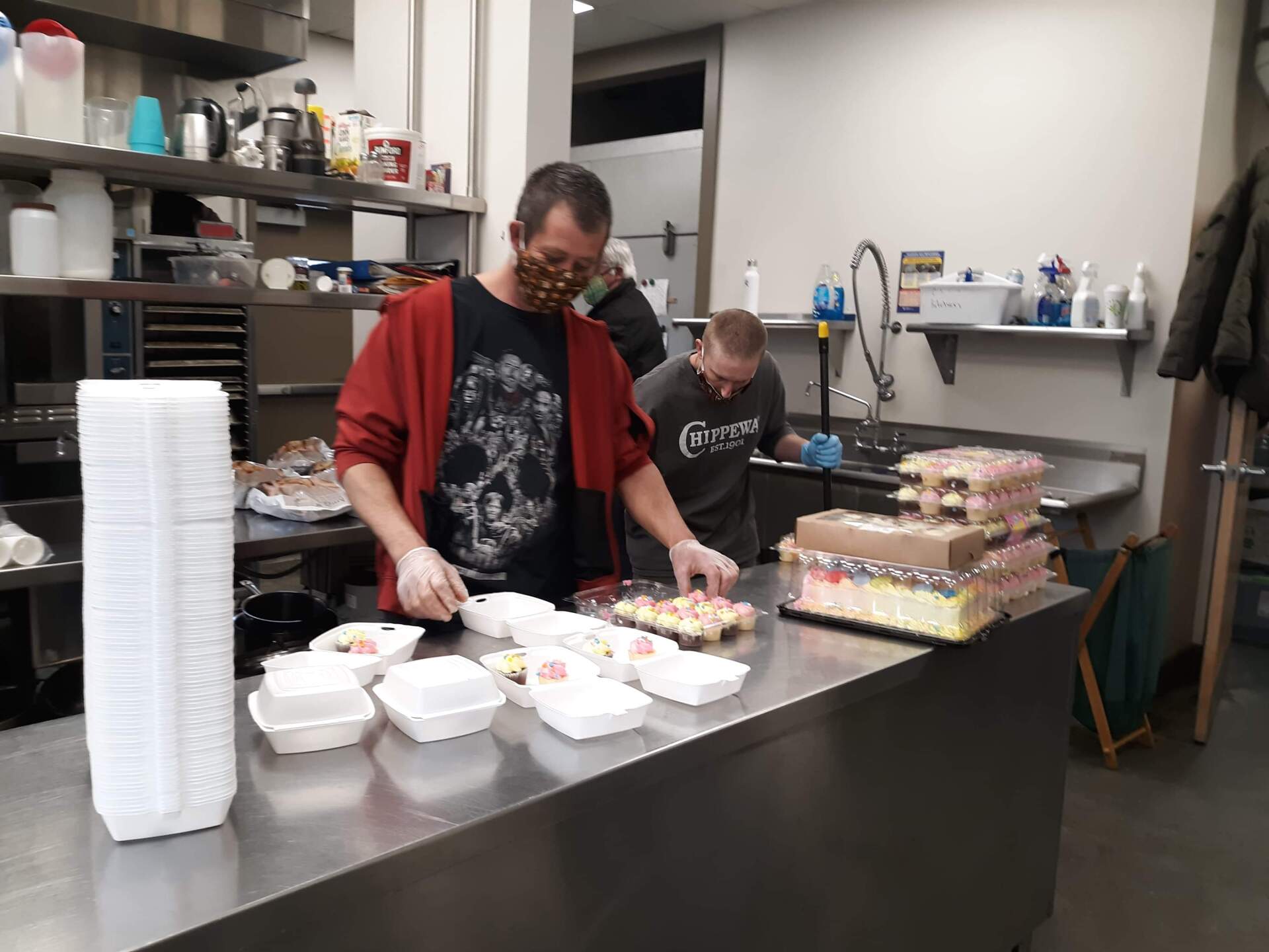 Two men are preparing food in a kitchen and one of them is wearing a mask.