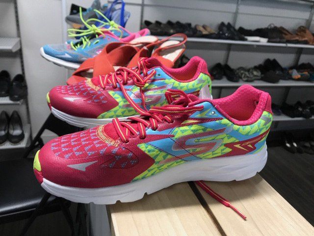 A pair of skechers running shoes are sitting on a wooden bench