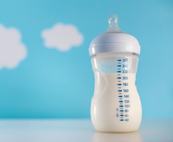 A baby bottle filled with milk is sitting on a table.