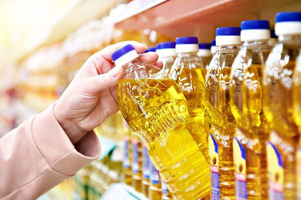 A person is holding a bottle of oil in a supermarket.