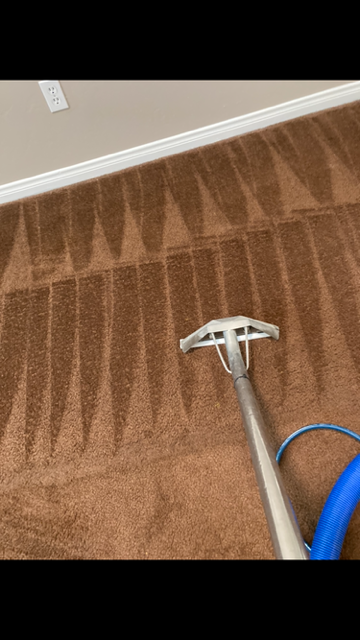 Man kneeling on carpet, spraying stain with cleaner and wiping with a cloth. Living room setting.