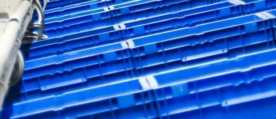 A row of blue plastic crates are stacked on top of each other on a conveyor belt - Engineering Tooling In Thornton, NSW