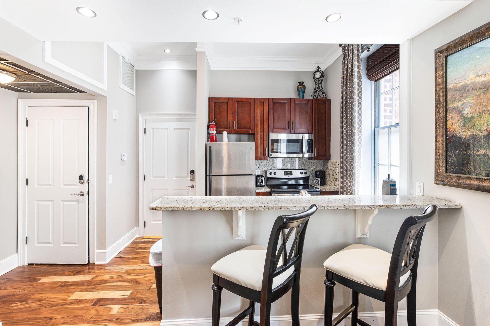 A small kitchen with a breakfast bar and two stools, next to a living area.
