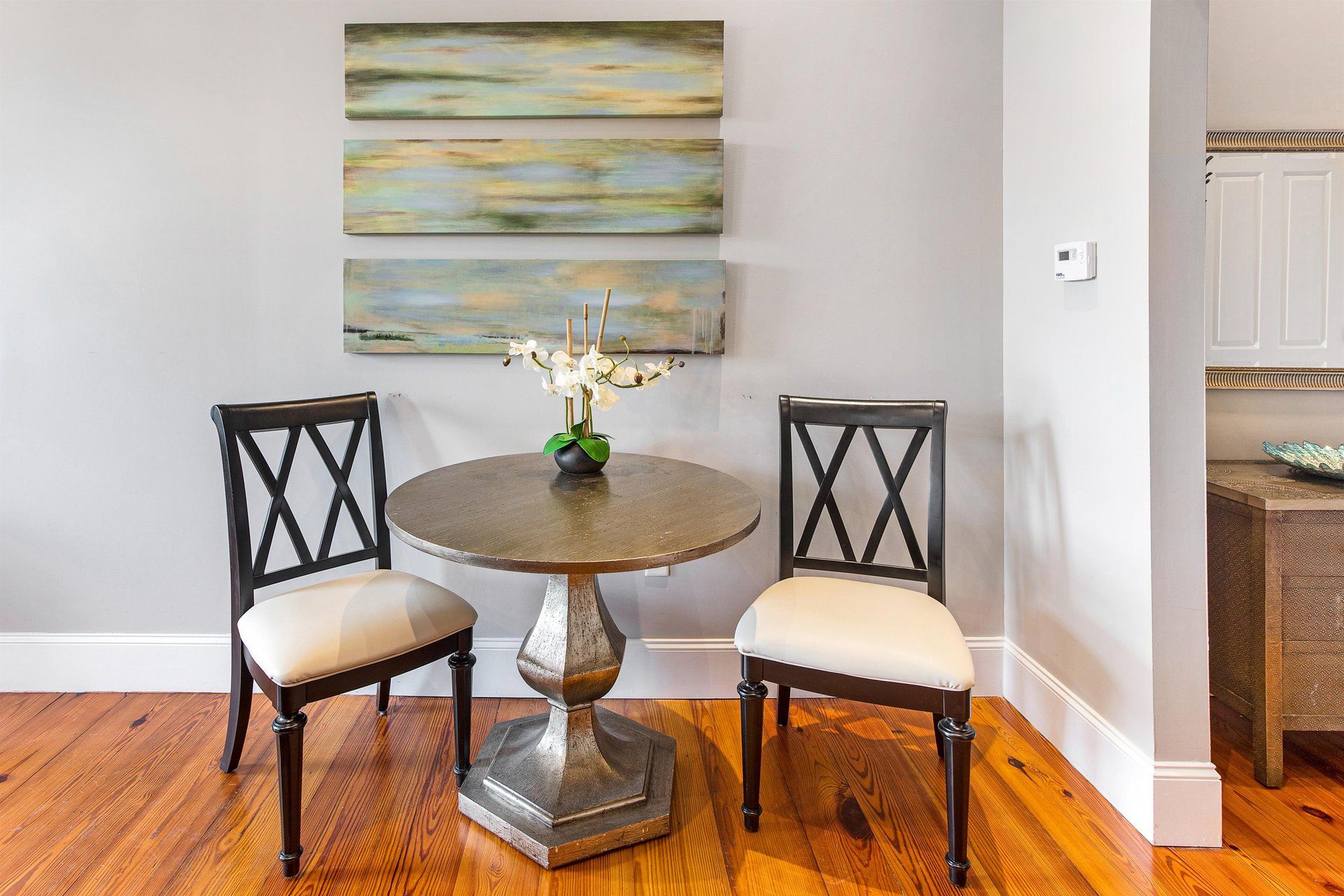 Two chairs and a table in front of a wall with artwork.