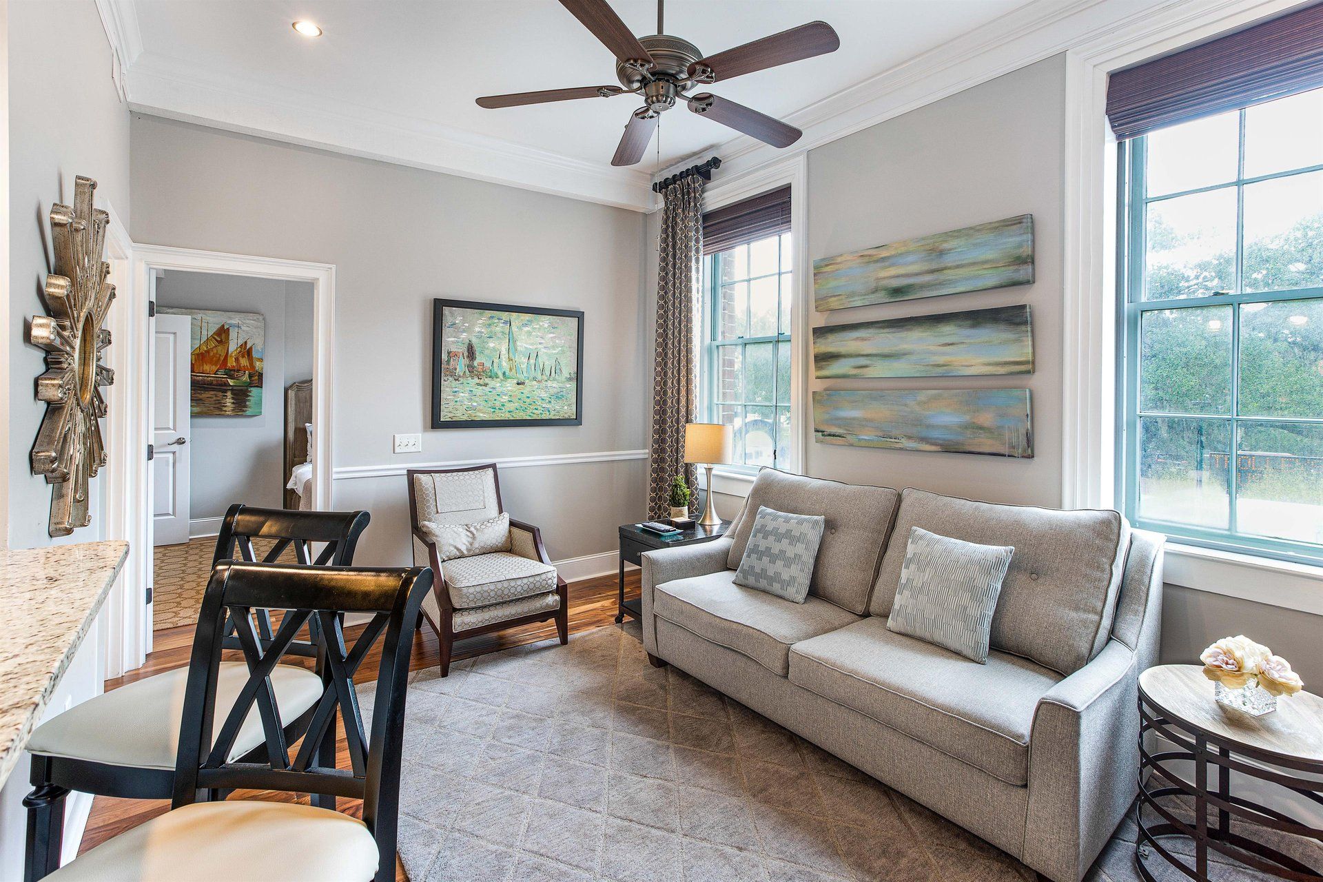Living room with gray walls, sofa, and artwork, with two windows and a doorway.