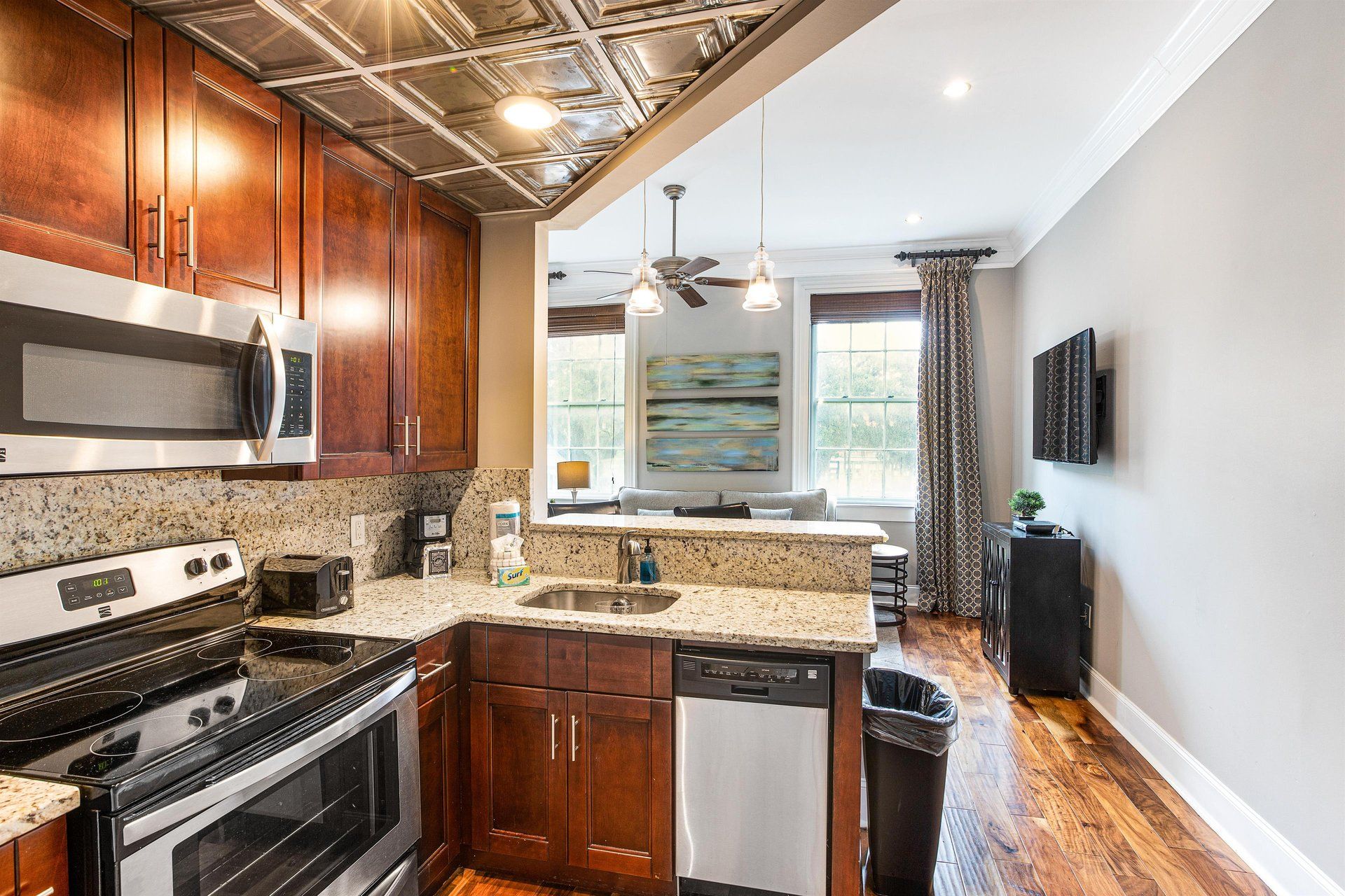 Kitchen with stainless steel appliances, granite countertops, and dark wood cabinets, open to a living area.