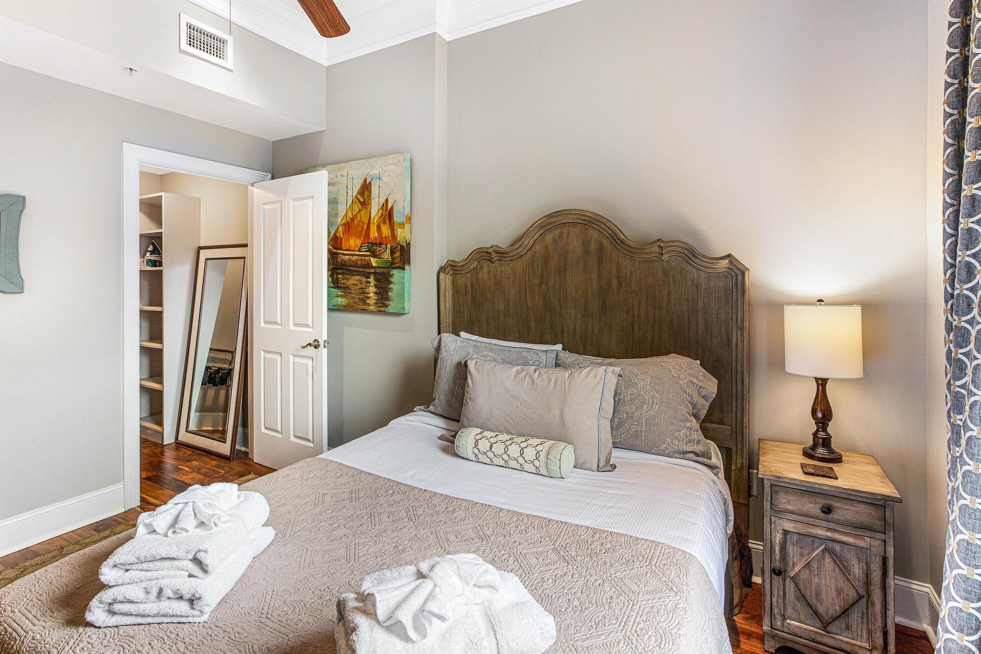 Bedroom with bed, nightstand, art, open closet. Neutral color scheme, natural light.