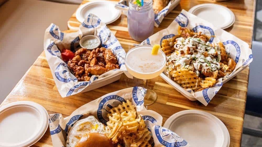 Table with food baskets: fried chicken, waffle fries, and drinks.