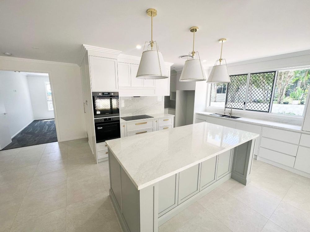 A Large Empty Room With a Kitchen and a Ceiling Fan — Werry Building Services in Boyne Island, QLD