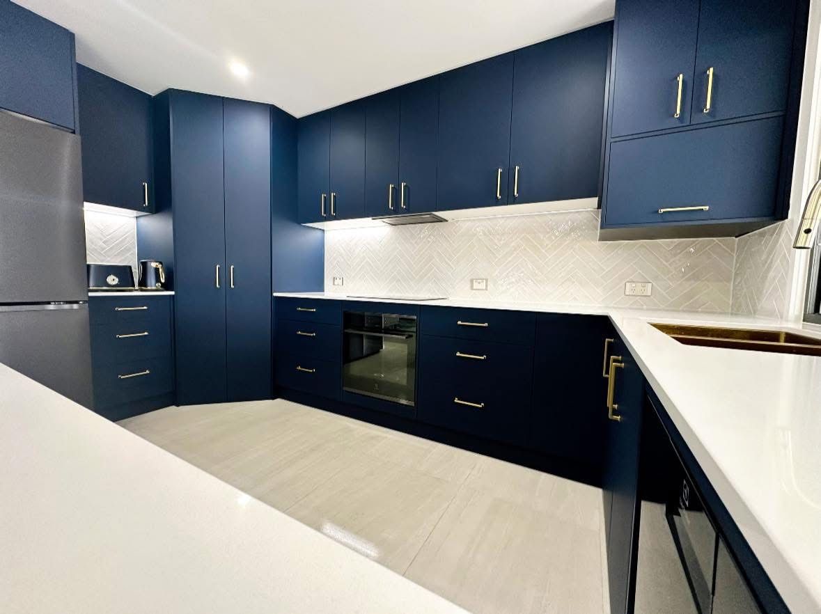 A Large Empty Room With a Kitchen and a Ceiling Fan — Werry Building Services in Boyne Island, QLD