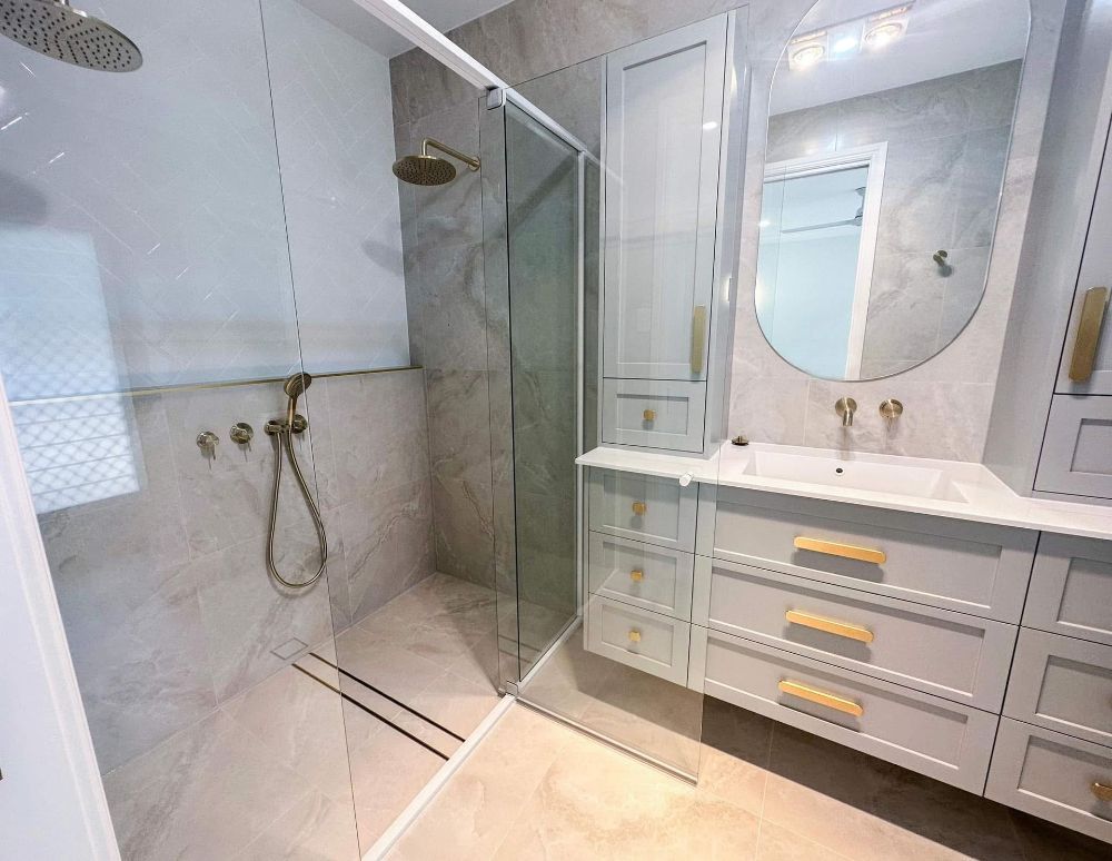 A Bathroom With a Sink, Mirror and Walk in Shower — Werry Building Services in Boyne Island, QLD
