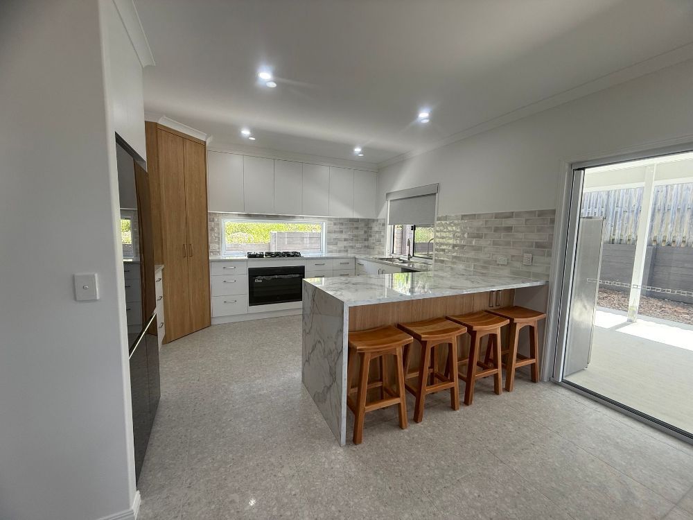 A Kitchen With White Cabinets and a Black Sink — Werry Building Services in Boyne Island, QLD