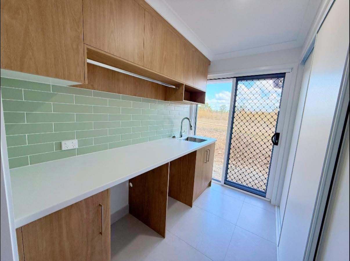 A Large Empty Room With a Kitchen and a Ceiling Fan — Werry Building Services in Boyne Island, QLD