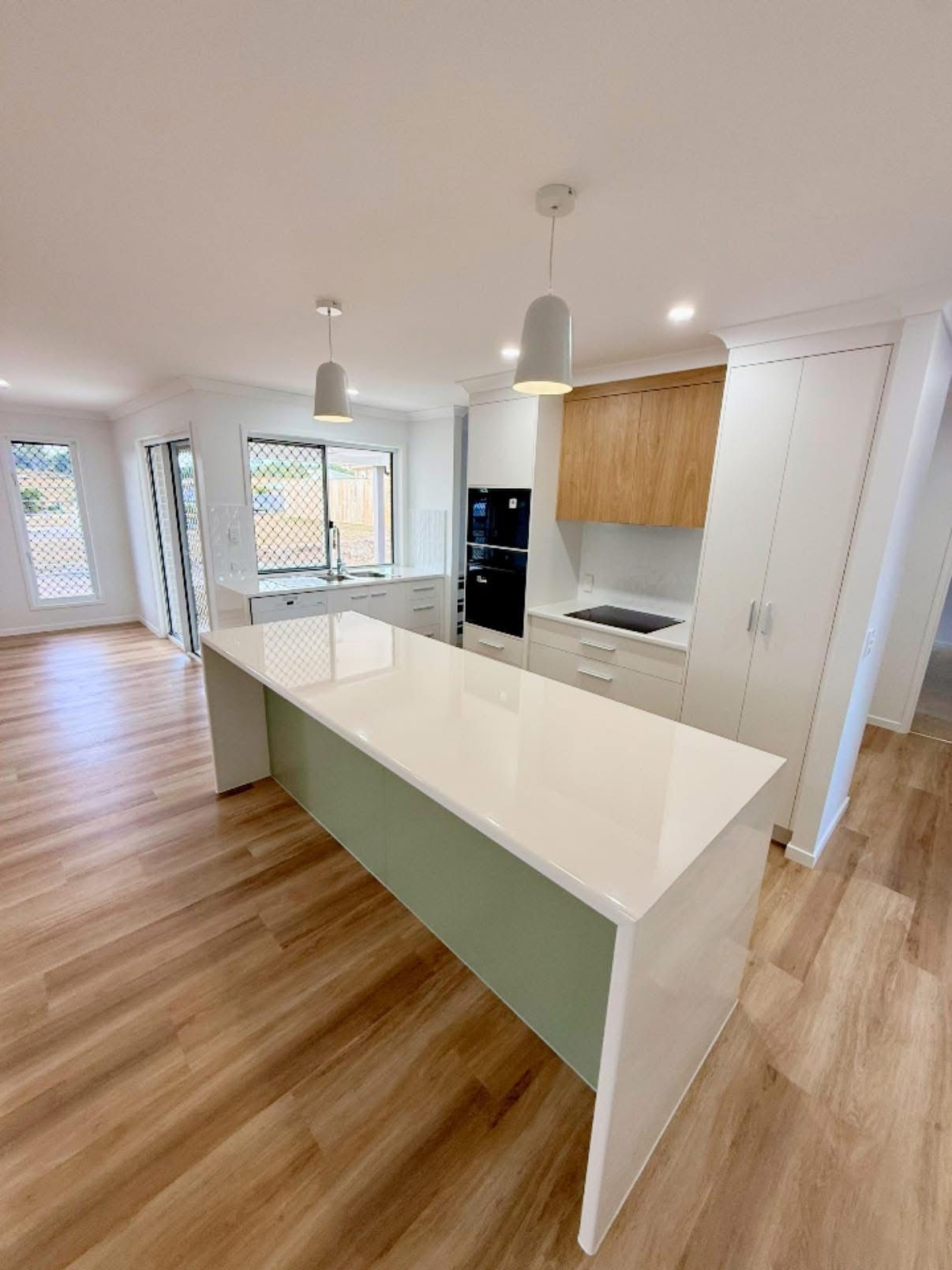 A Large Empty Room With a Kitchen and a Ceiling Fan — Werry Building Services in Boyne Island, QLD