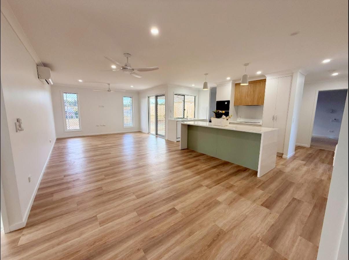 A Large Empty Room With a Kitchen and a Ceiling Fan — Werry Building Services in Boyne Island, QLD
