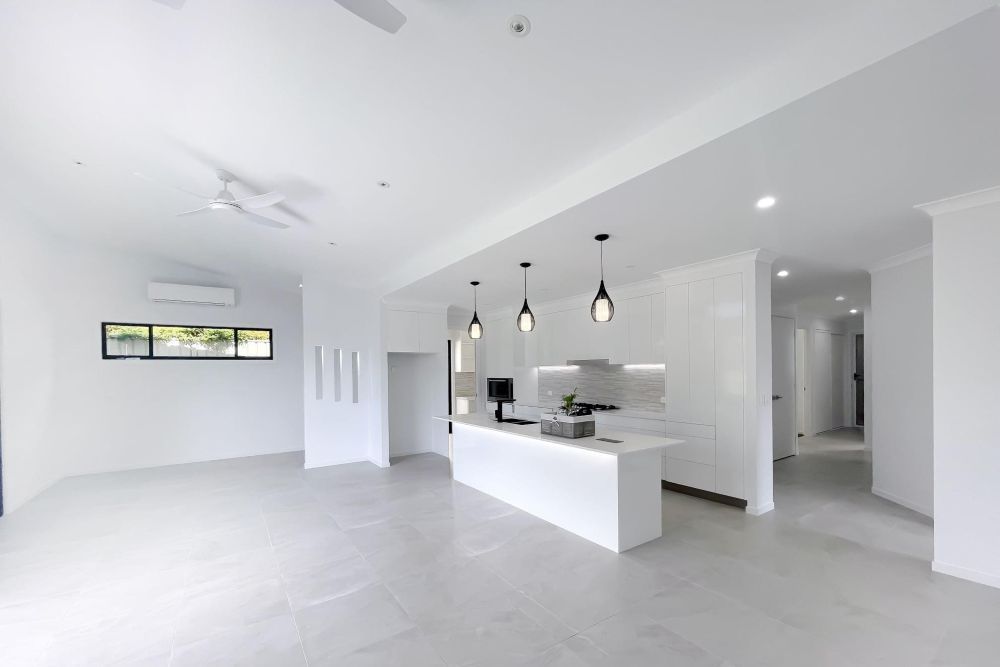 A Large Empty Room With White Walls and a Kitchen — Werry Building Services in Boyne Island, QLD