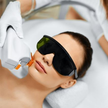 Woman receiving facial laser treatment; wearing protective eyewear.
