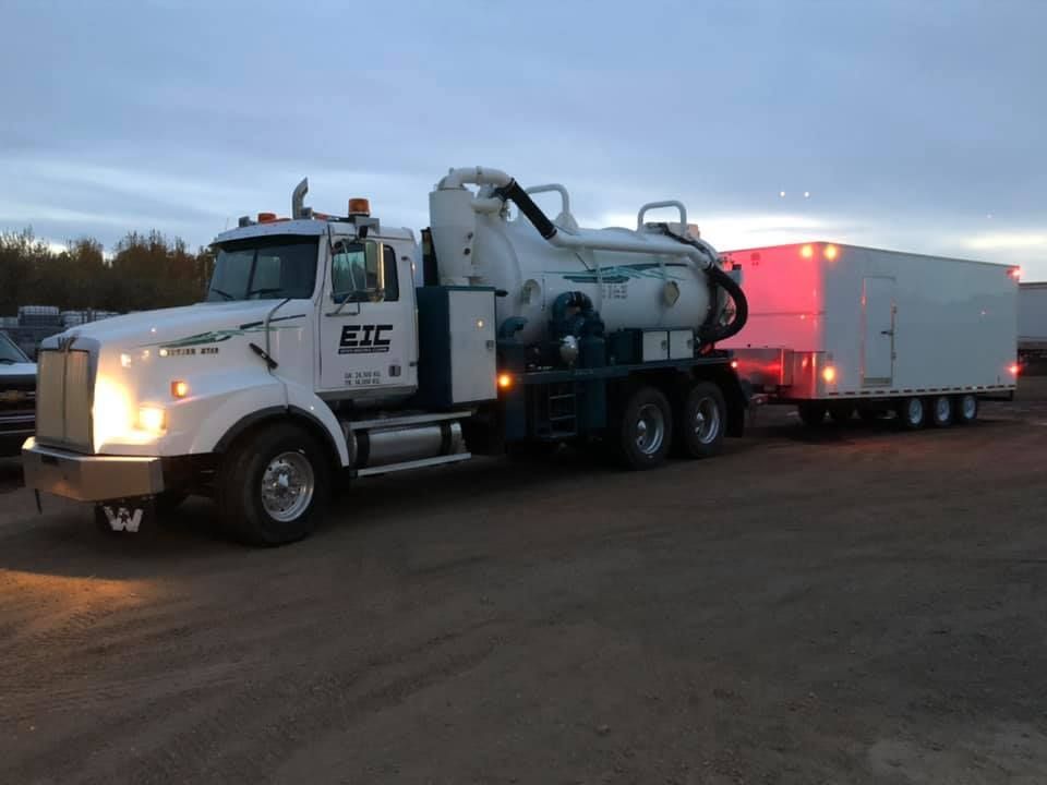 A vacuum truck with a trailer attached to it