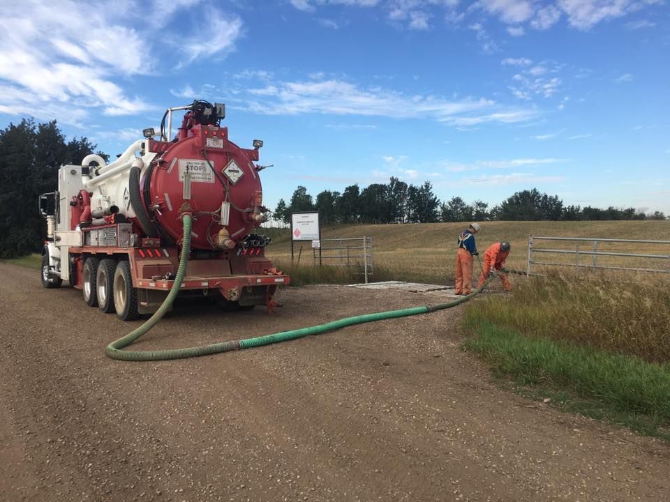 A vacuum truck is pumping water into a field.