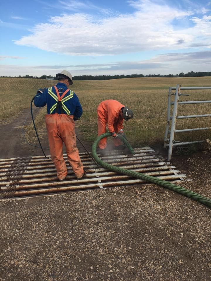 Two men are cleaning a fence with a hose.
