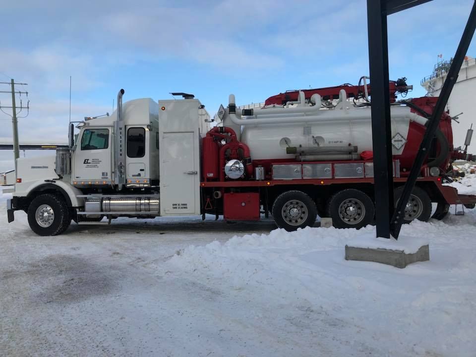 A white and red truck is parked in the snow.