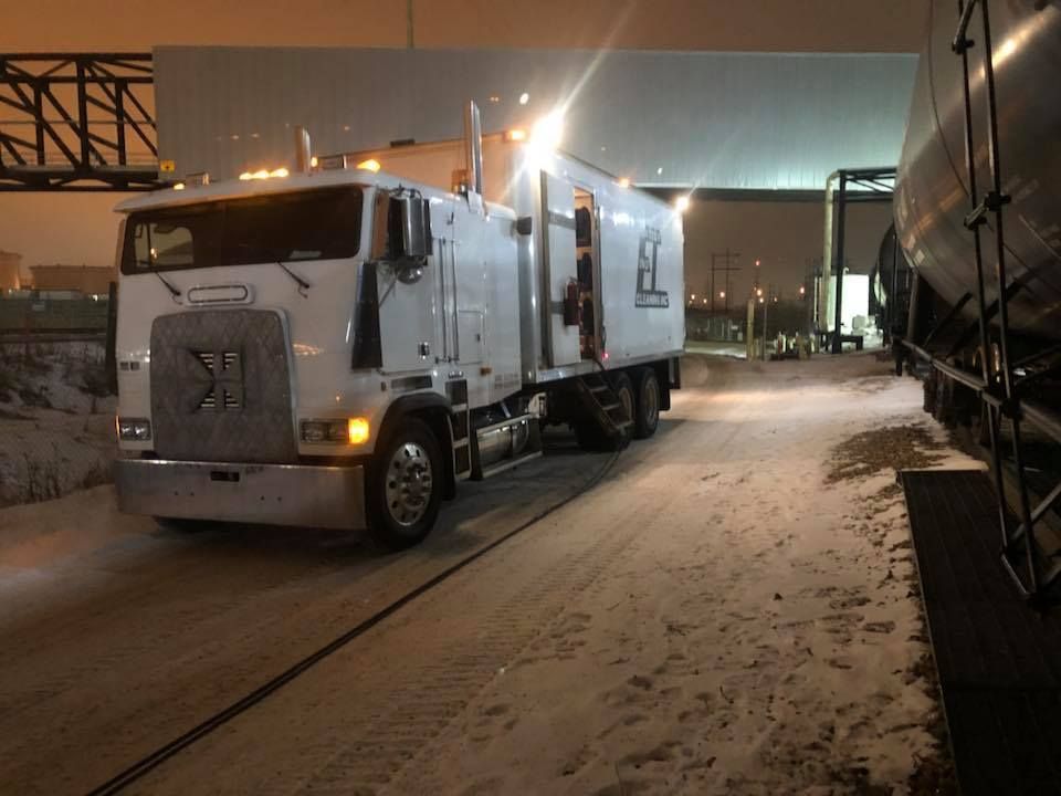 A white semi truck is parked on a snowy road at night