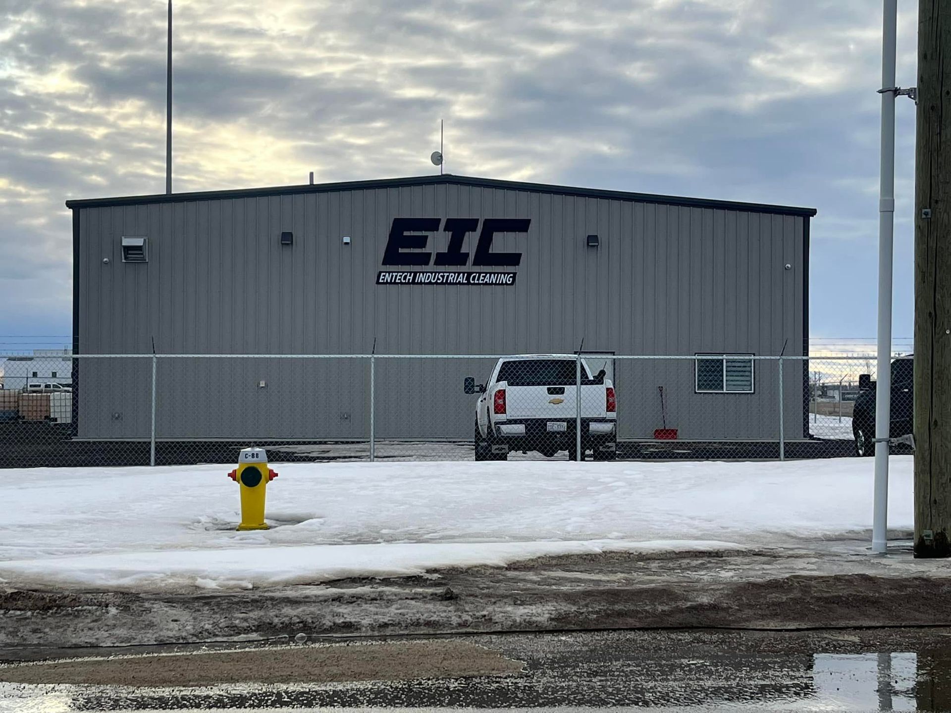 A white truck is parked in front of a building that says eic