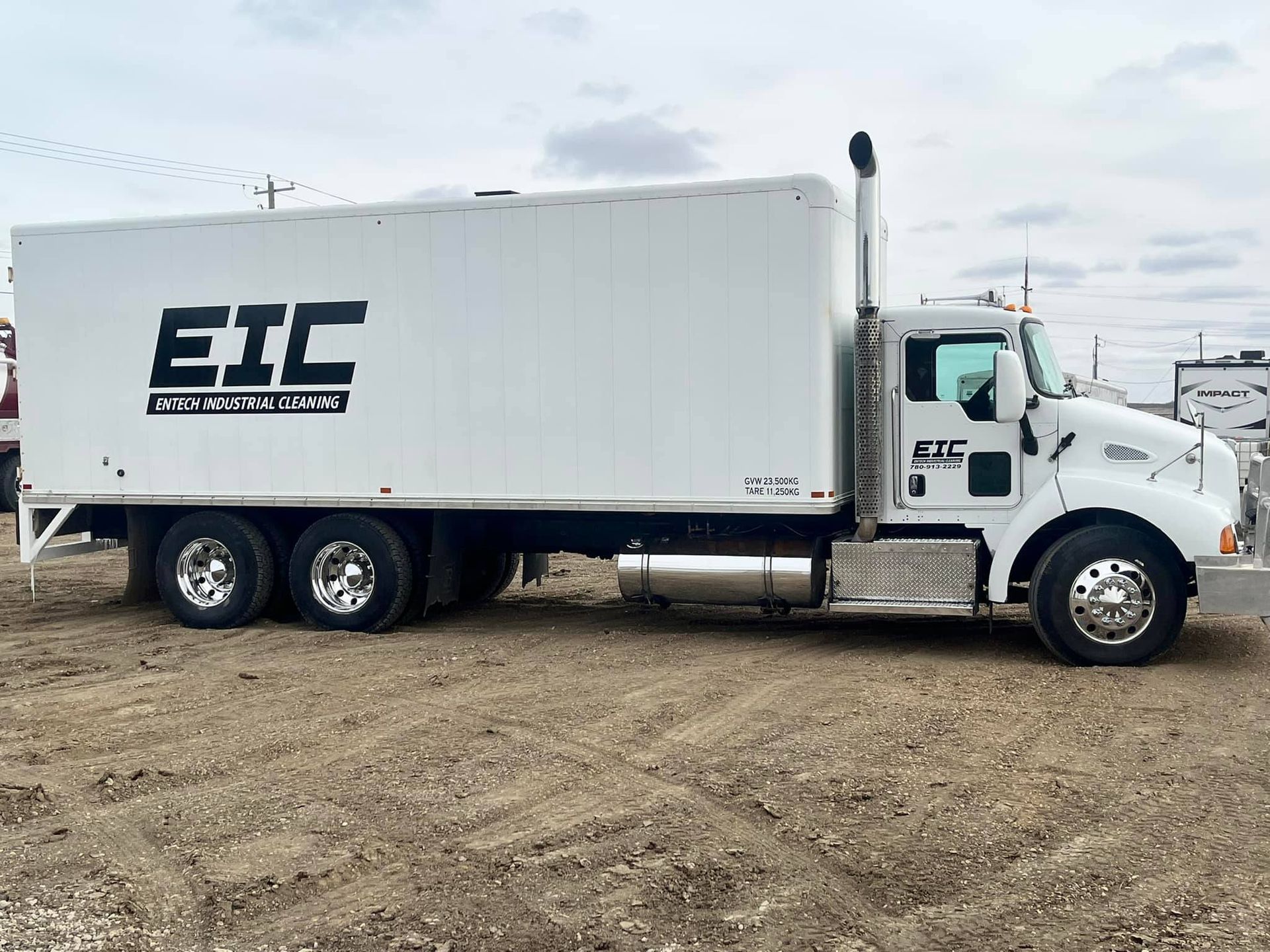 A white truck with the word eic on the side is parked in a dirt field.