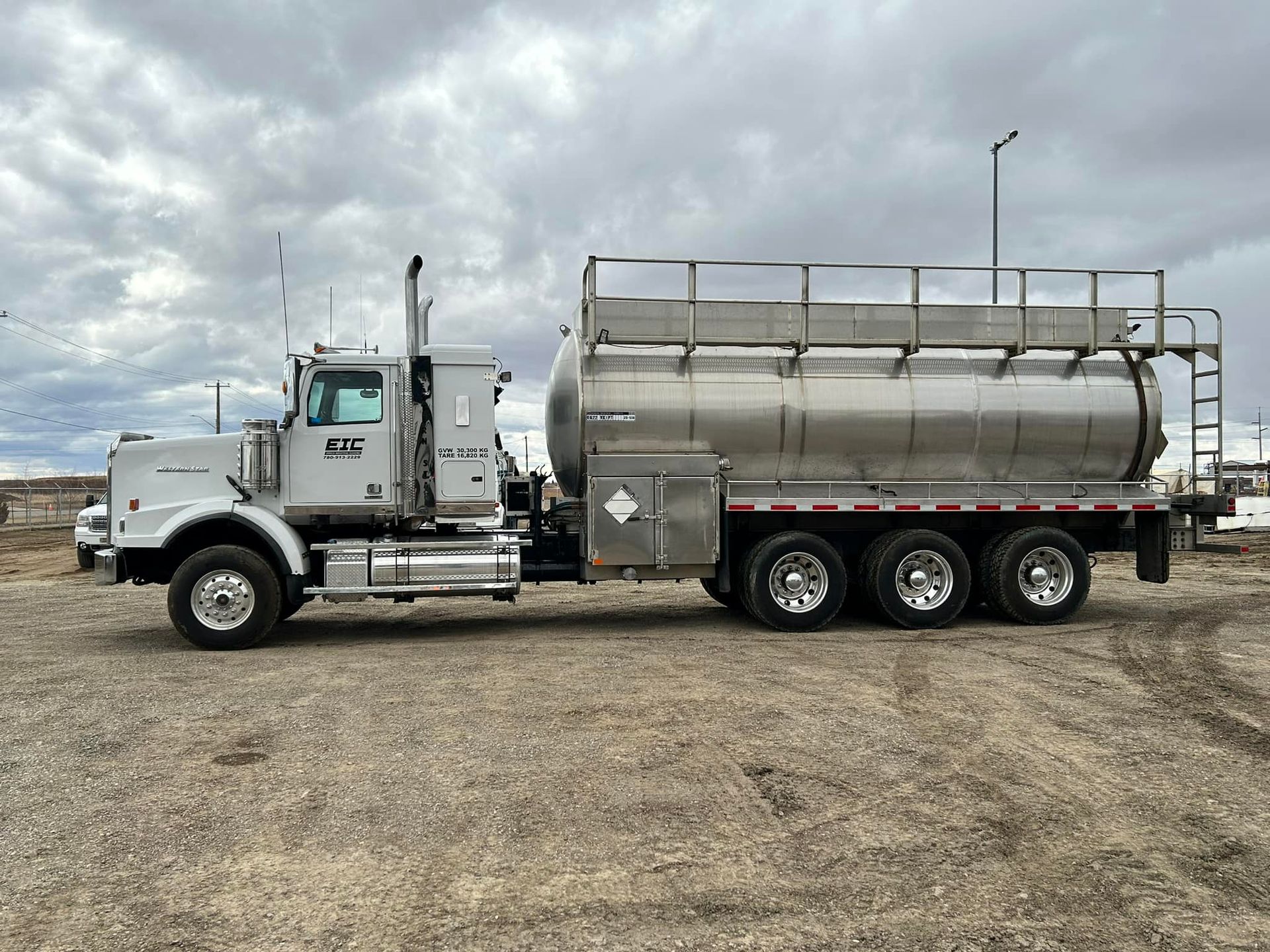 A large tanker truck is parked in a dirt field.