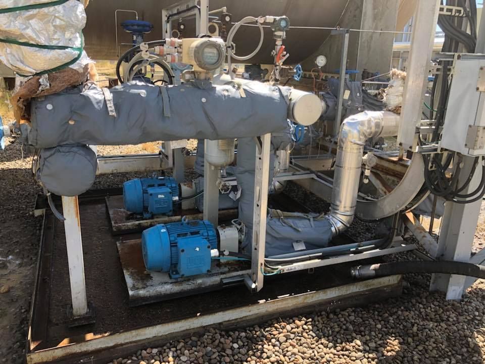 A bunch of pipes and motors are sitting on top of a pile of gravel.