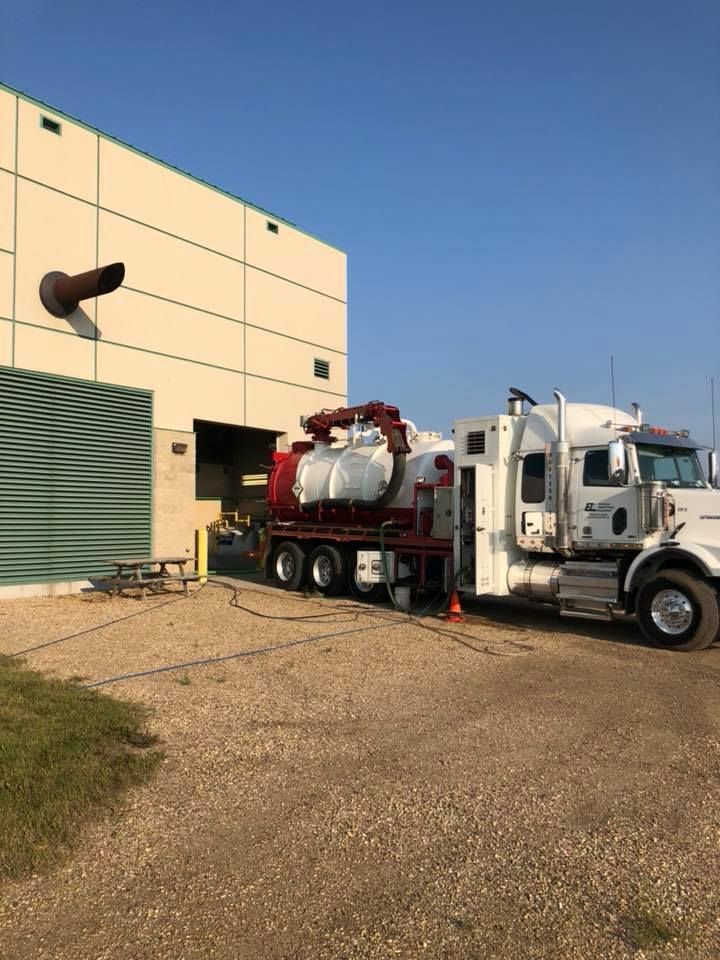 A vacuum truck is parked in front of a building.