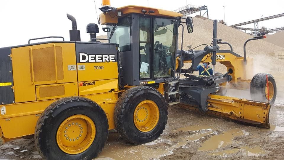 A yellow deere tractor is driving through a muddy field.