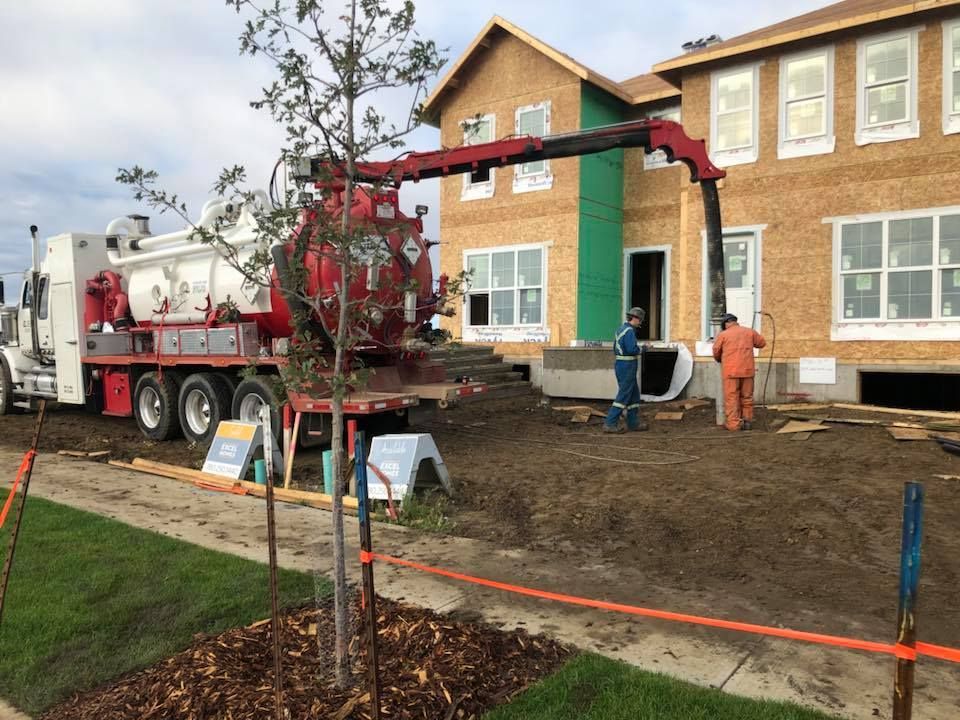 A vacuum truck is parked in front of a house under construction.