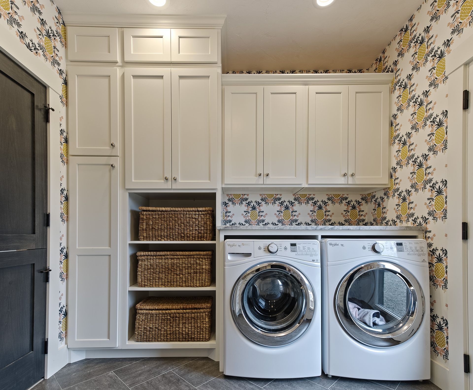 Laundry room with washer dryer combo and bins for clothes.