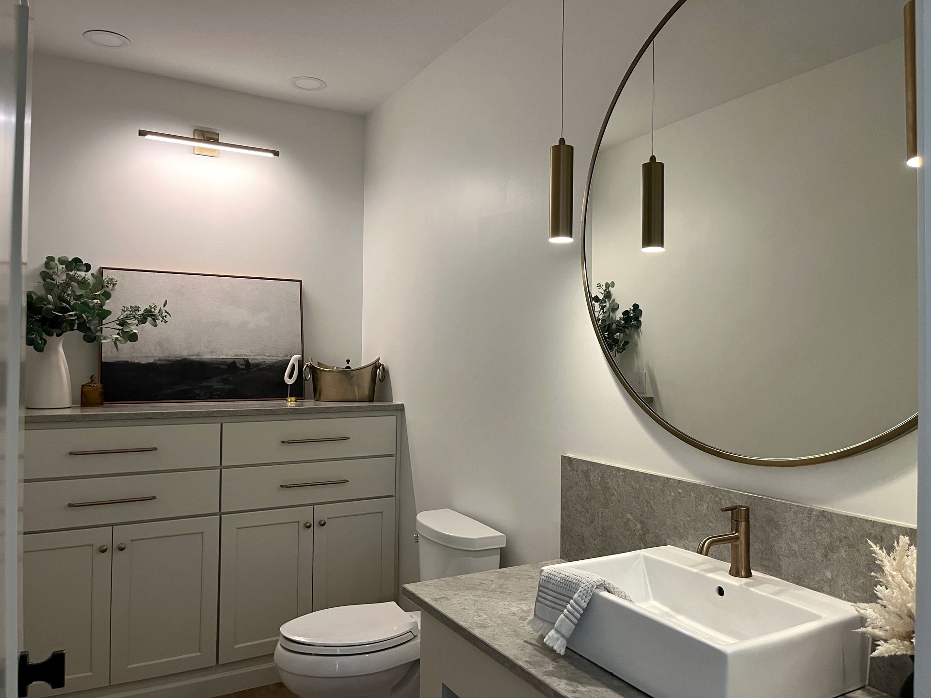 A small bathroom with multiple drawers, a toilet, and sink setup with mirror.