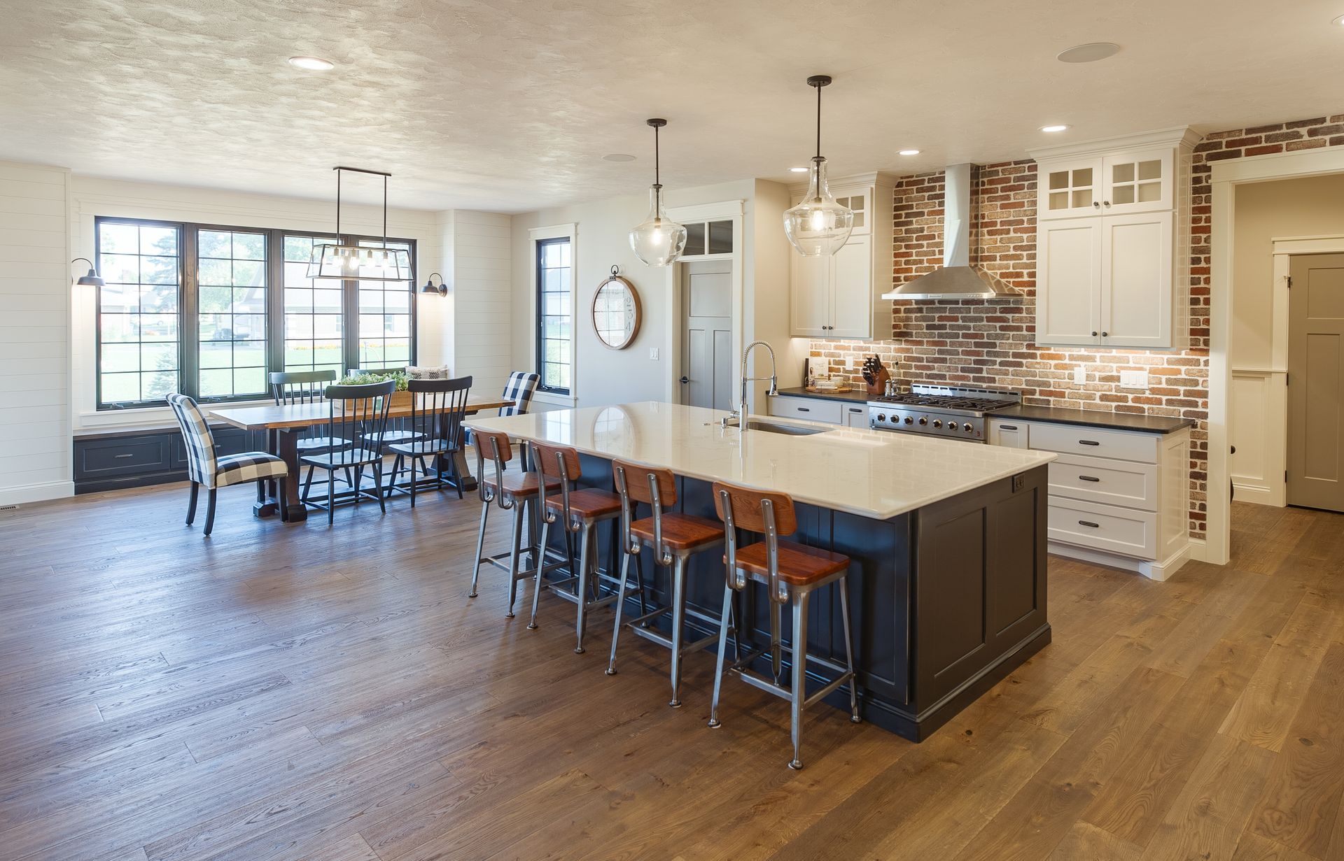 Island table with hanging lights and a second table to the left near a window.