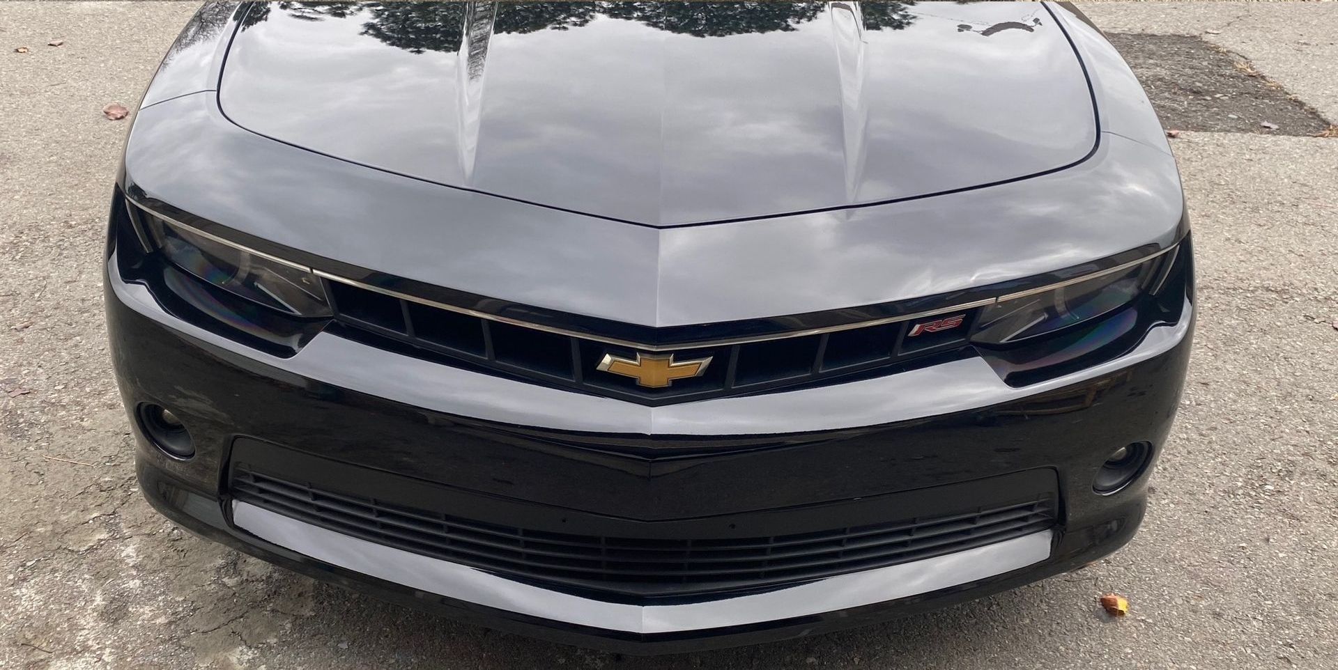 a black and white chevrolet camaro is parked on the side of the road .