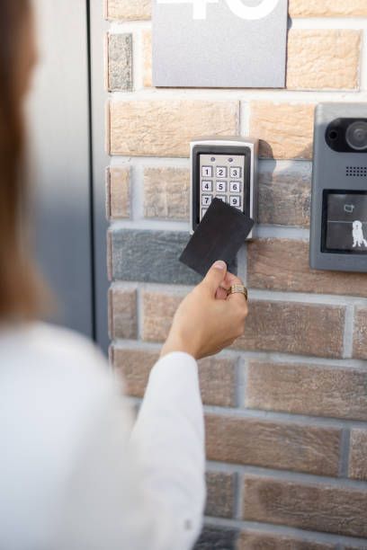 A man in a blue hat is installing a device on a wall