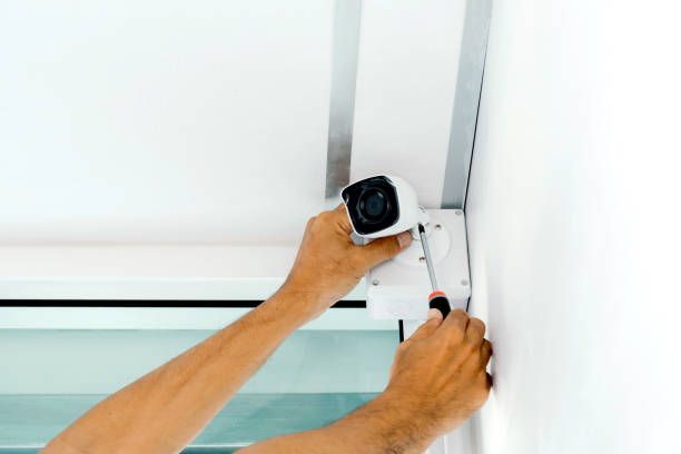 A person is fixing a security camera with a screwdriver.