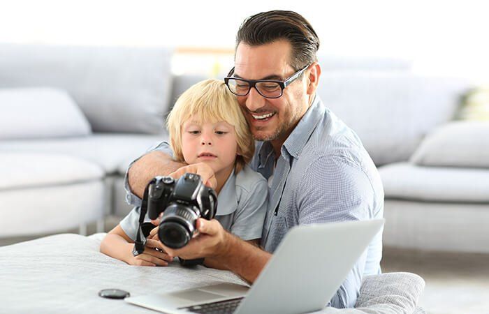 Father and son holding a camera