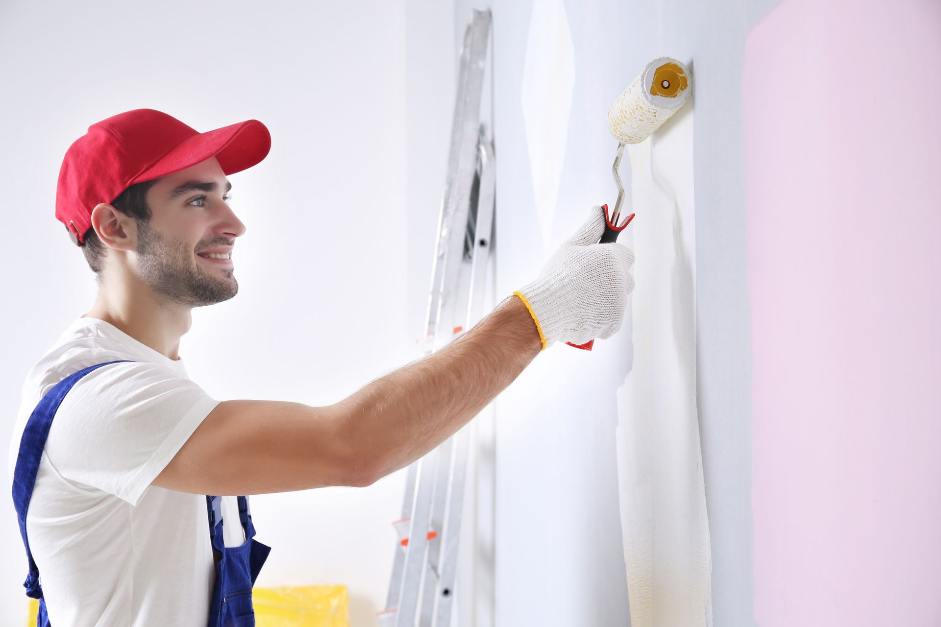 A man is painting a wall with a paint roller.