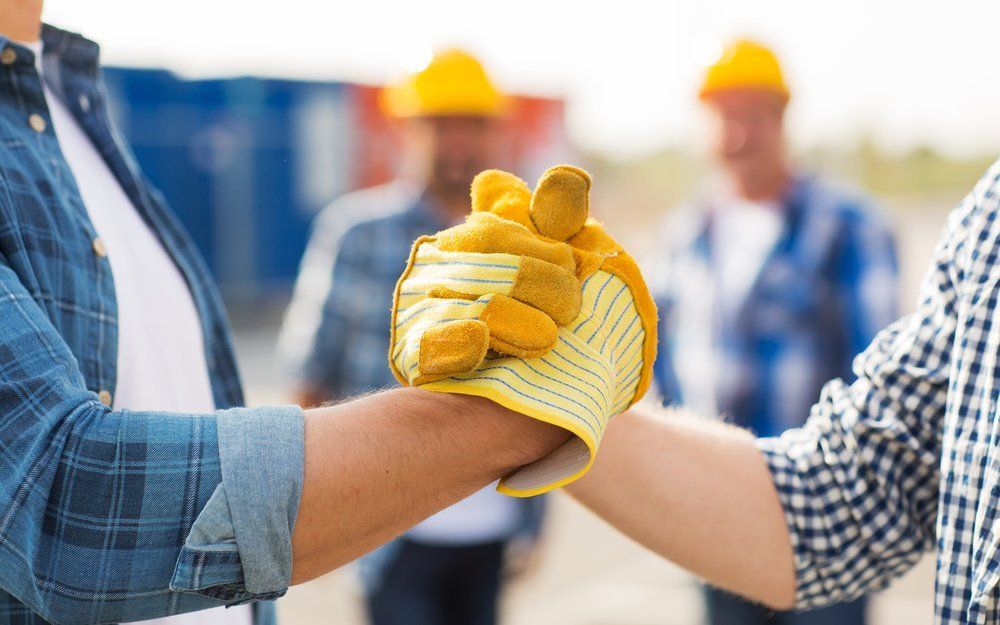 A group of construction workers are shaking hands on a construction site.