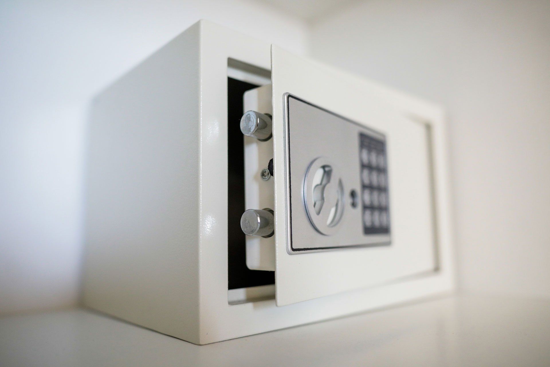 A white safe with the door open is sitting on a table.