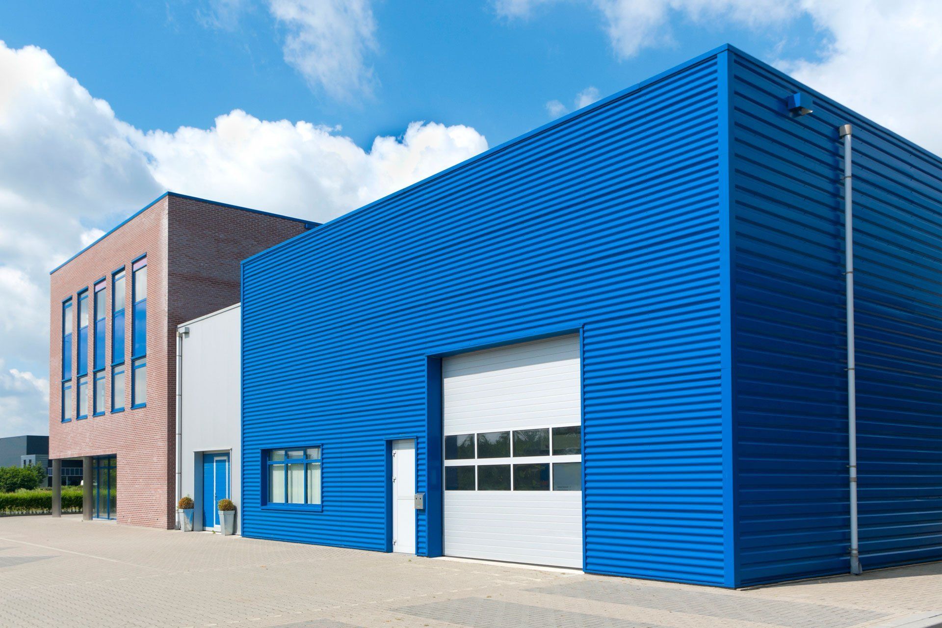 A blue building with a white garage door is next to a pink building.