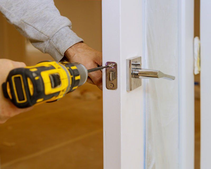A person is installing a door handle with a drill.