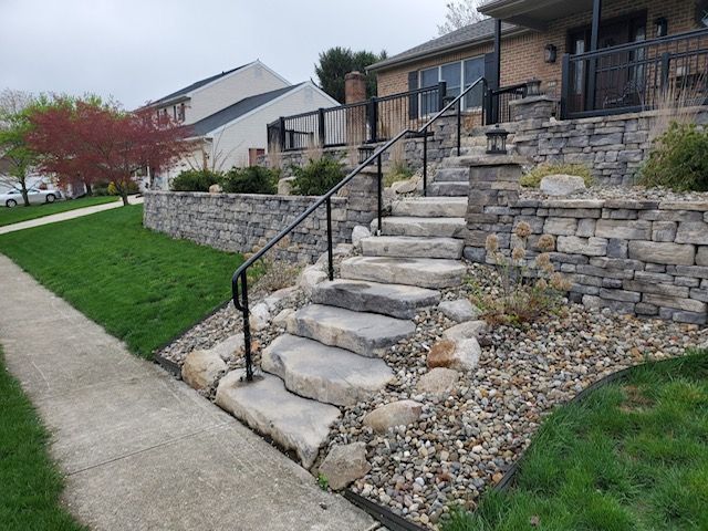 A set of stairs leading up to a house with a stone wall.