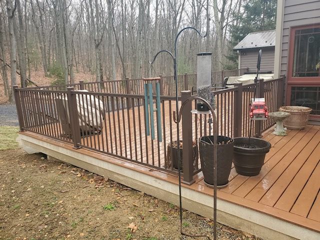 A deck with a fence and potted plants on it.