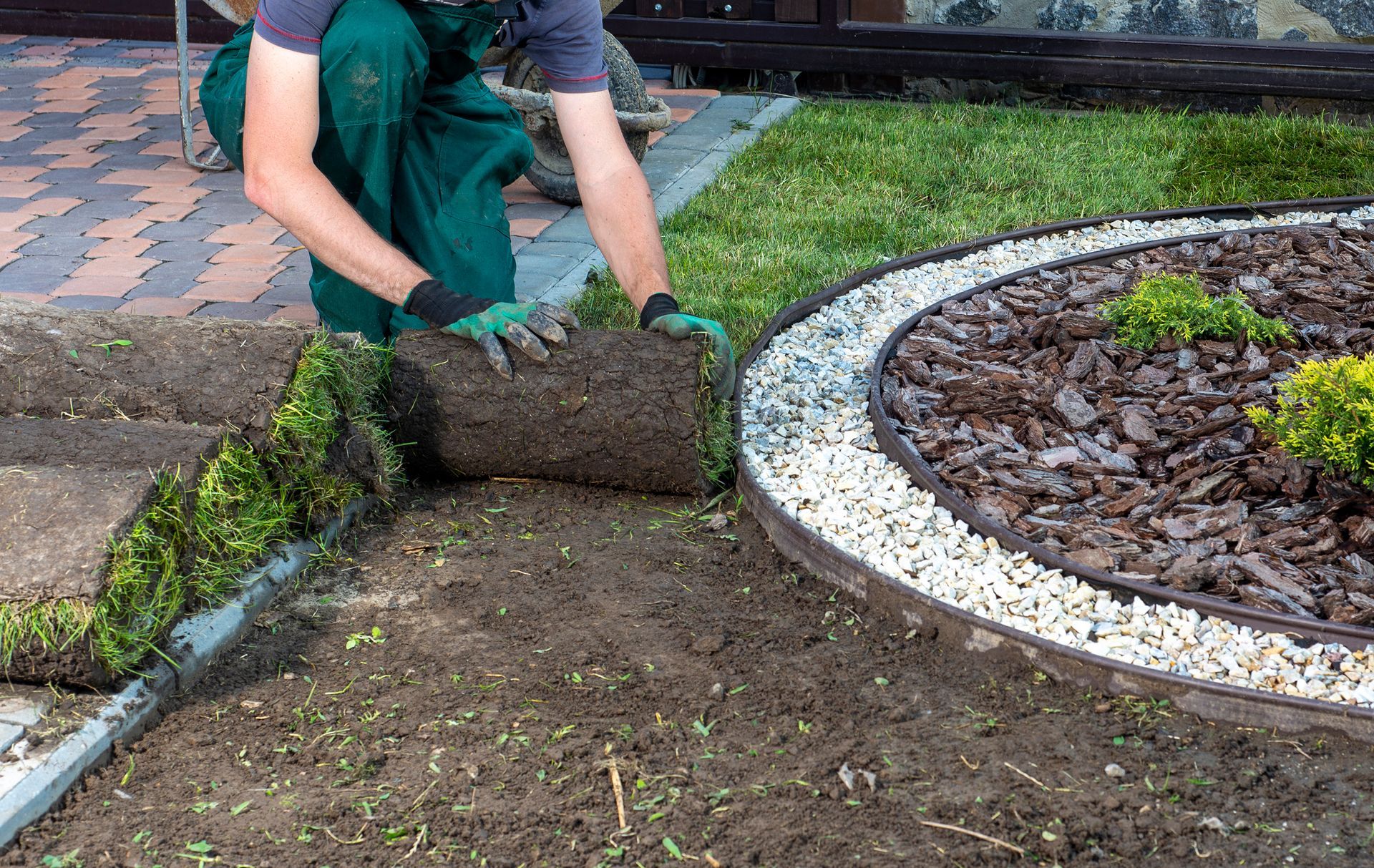 Close-up of a landscaper spreading mulch in a landscape, enhancing aesthetics and weed control.